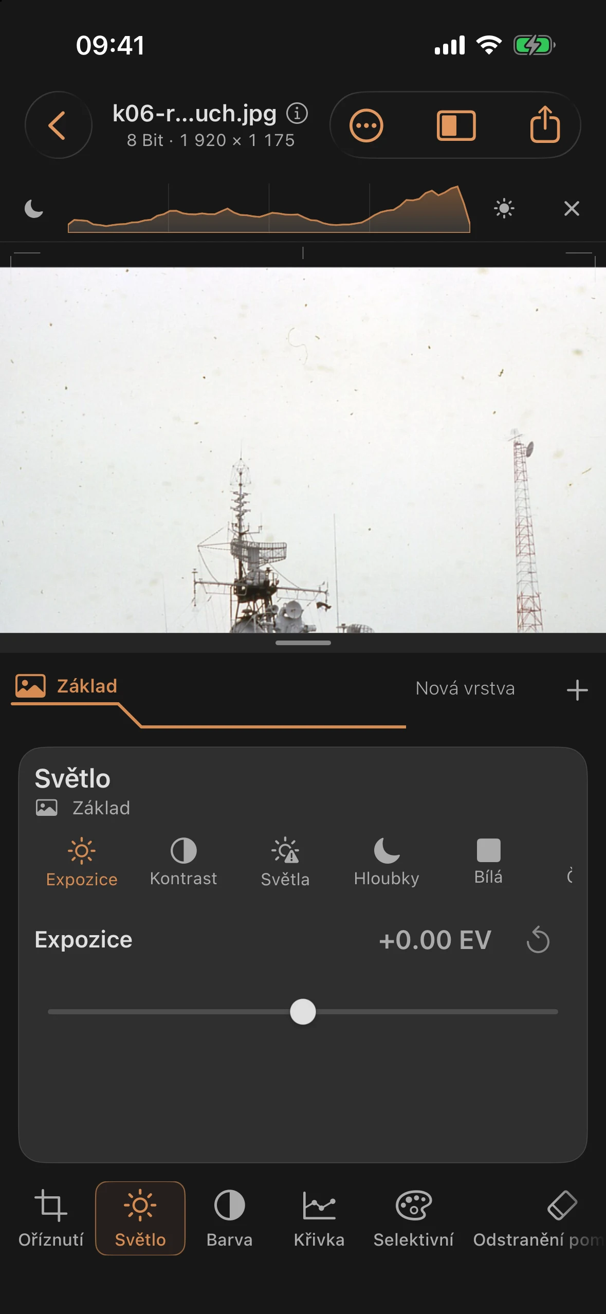 Zvětšený výřez ze skenu historické barevné fotografie s ohnutým tmavým prachovým vláknem nad levým lodním stěžněm