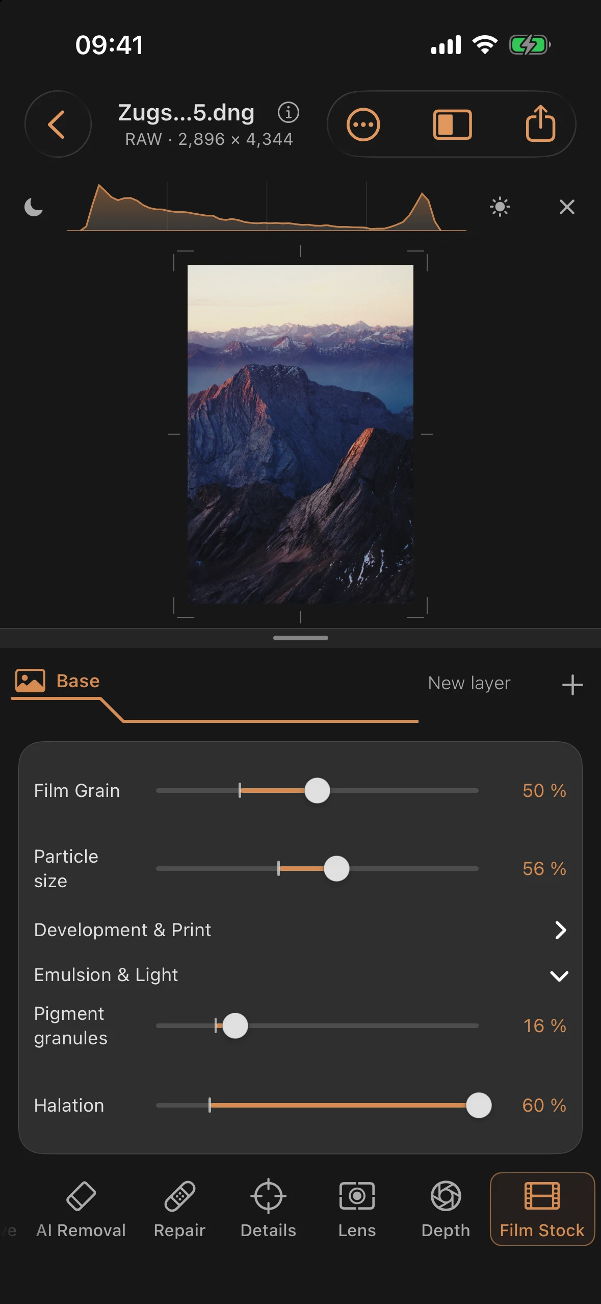 Color mountain image with visible film grain and warm halation glow along bright ridge edges and the horizon, Film Stock panel open