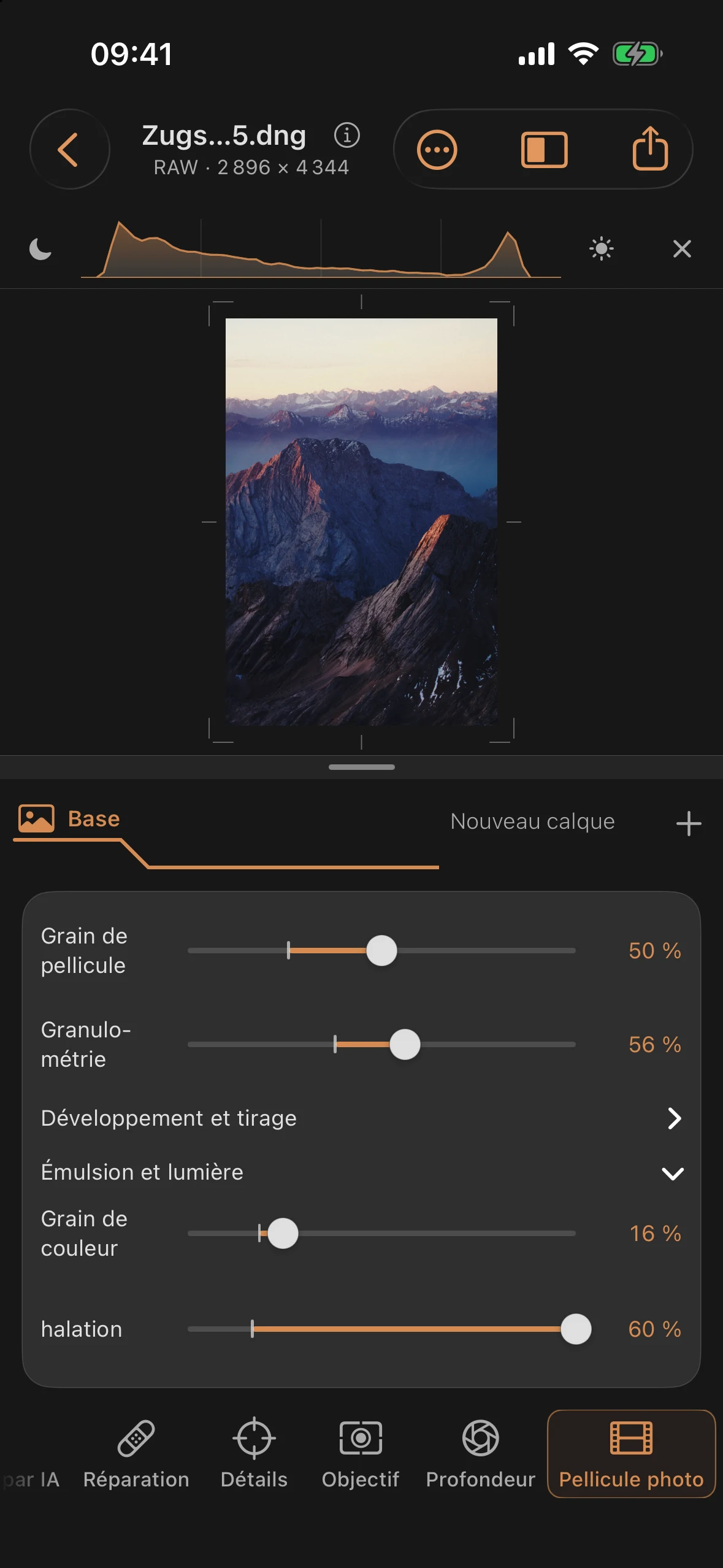 Photo de montagne en couleur présentant un grain de pellicule visible et un halo chaleureux sur les arêtes claires et à l'horizon ; panneau de pellicule photographique ouvert