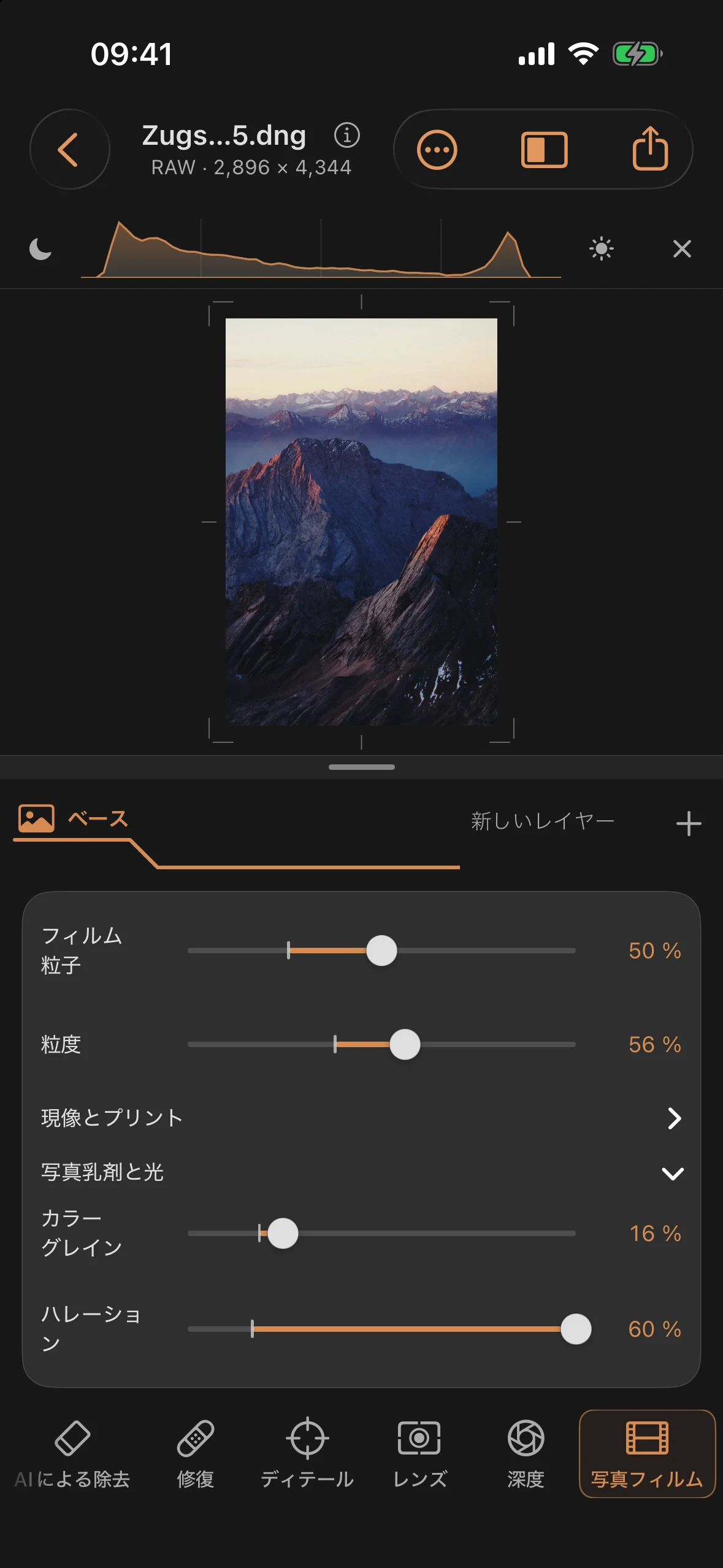 フィルムの粒子が目立ち、明るい尾根の縁や地平線に温かみのある光の輪が浮かび上がるカラーの山岳写真。写真フィルムのパネルが開かれている。